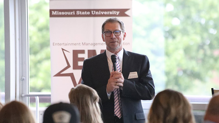 Dr. Philip Rothschild speaking to students during entertainment management graduation ceremony.