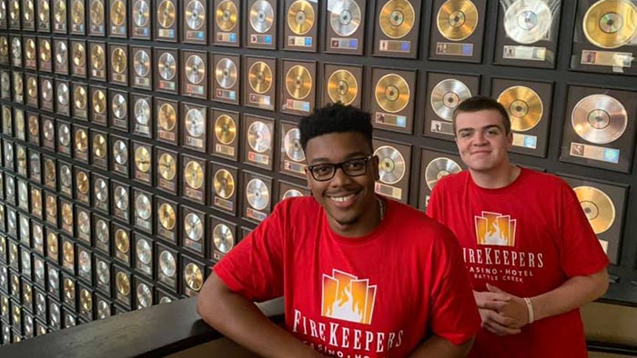 Entertainment management students next to record collection. 